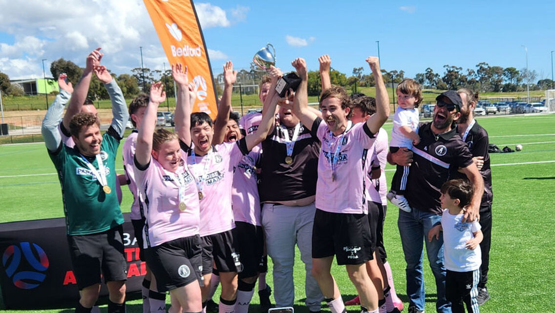 Group of people on field raising their hands with an orange banner behind them