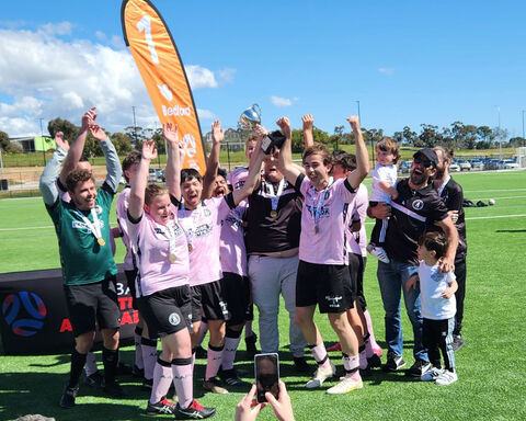 Group of people on field raising their hands with an orange banner behind them