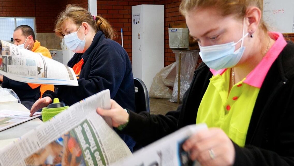 Women wearing face mask going through newspaper