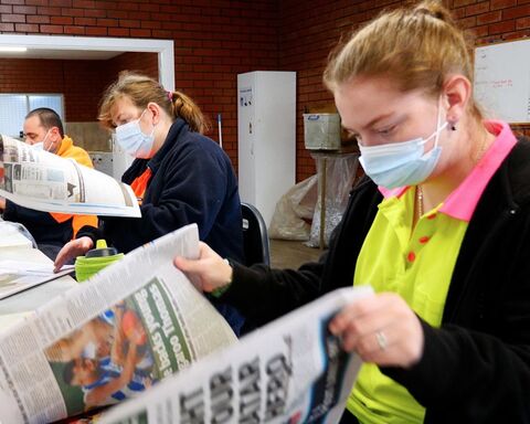 Women wearing face mask going through newspaper