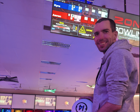 Man with bowling ball smiling