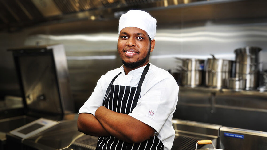 Chef wearing black colour stripped apron with arms crossed