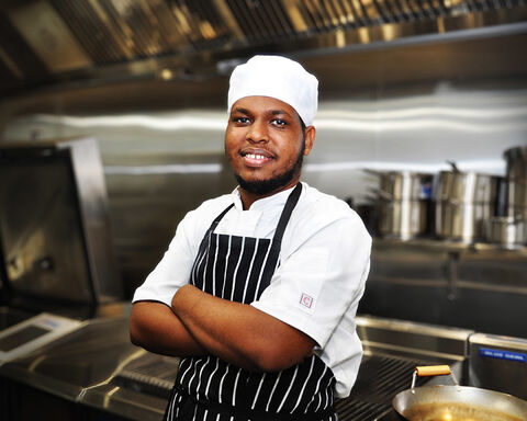 Chef wearing black colour stripped apron with arms crossed
