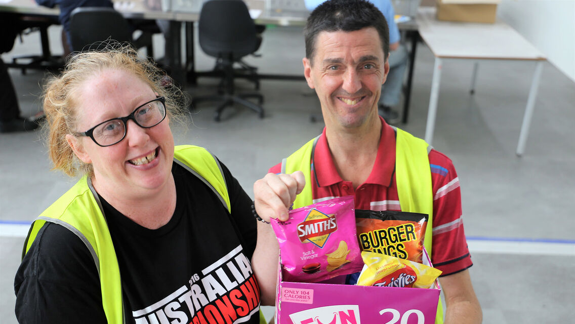 Two Bedford supported employees hold bags of chips