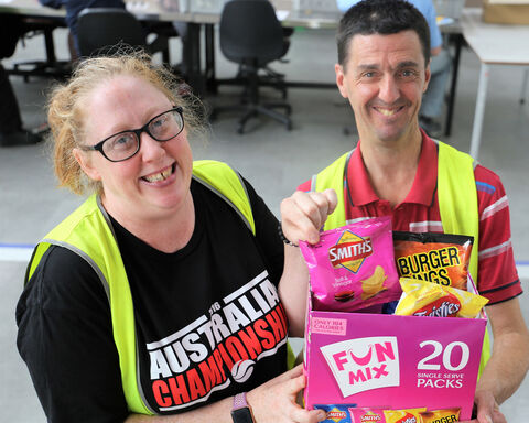 Two Bedford supported employees hold bags of chips