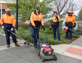 Four men holding brush cutter, mower and blower