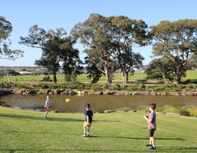Kids playing with a ball in greenery with trees nearby