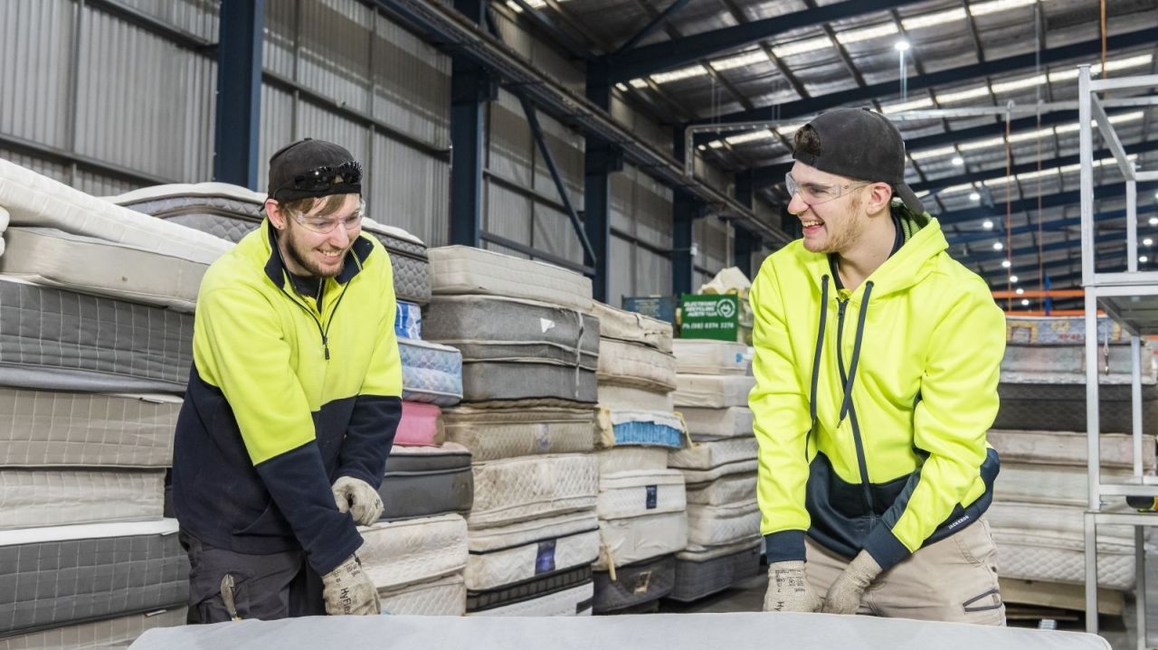 Two people at a mattress recycling warehouse
