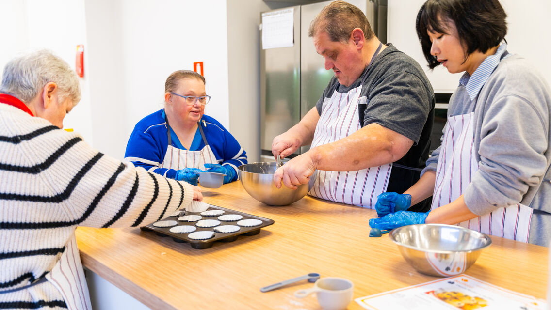 Group of individuals wearing aprons and mixing in bowls
