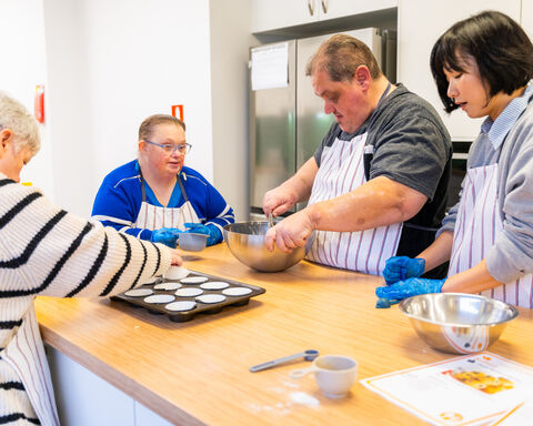 Group of individuals wearing aprons and mixing in bowls