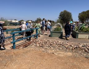 Group of people crossing a bridge and standing next to plants