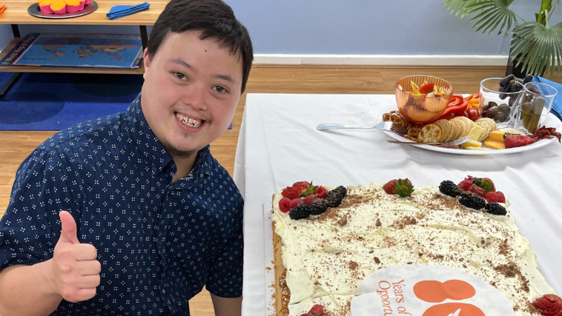 Man doing thumps up next to cake