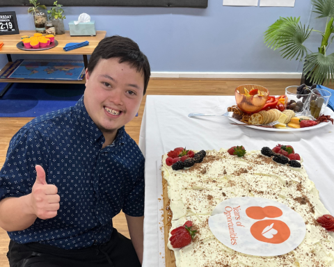 Man doing thumps up next to cake