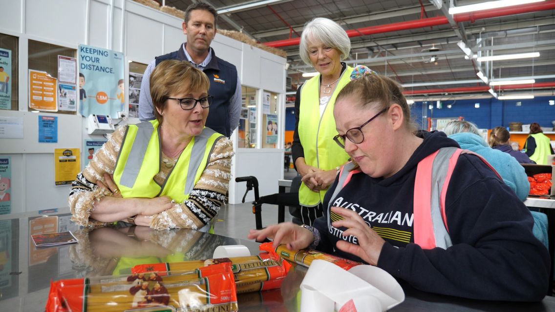 Group of people wearing hi-vis vests packing pasta