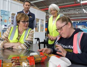 Group of people wearing hi-vis vests packing pasta