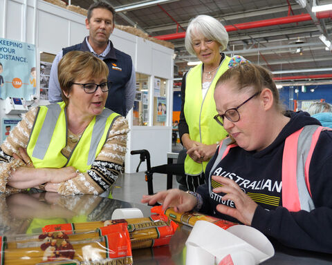Group of people wearing hi-vis vests packing pasta