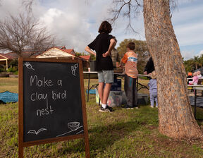 Kids standing next to tree next to a black board
