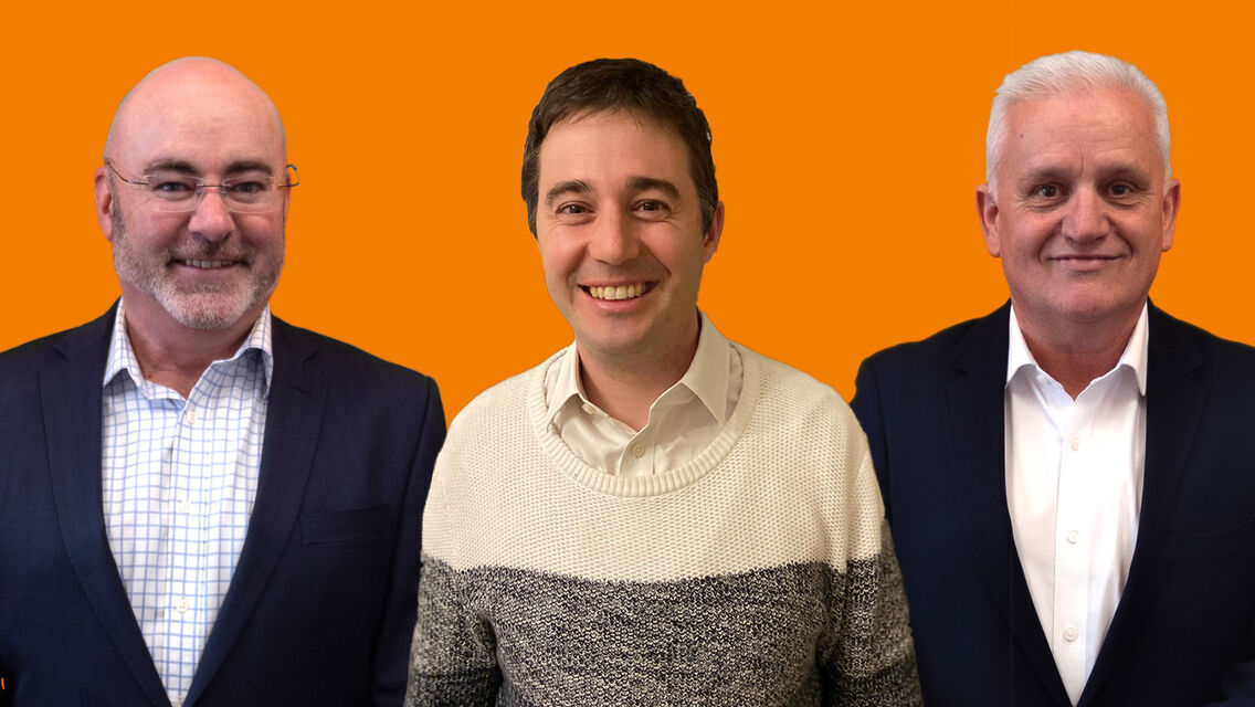 Three men on ornage background standing next to each other and smiling at camera