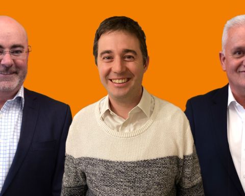 Three men on ornage background standing next to each other and smiling at camera