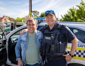 Police officer standing alongside a man in front of police car
