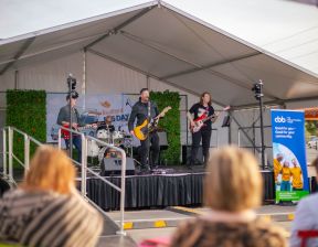 Three individuals singing on stage with guitars