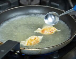 A close-up shot of cooking dumplings in a frying pan