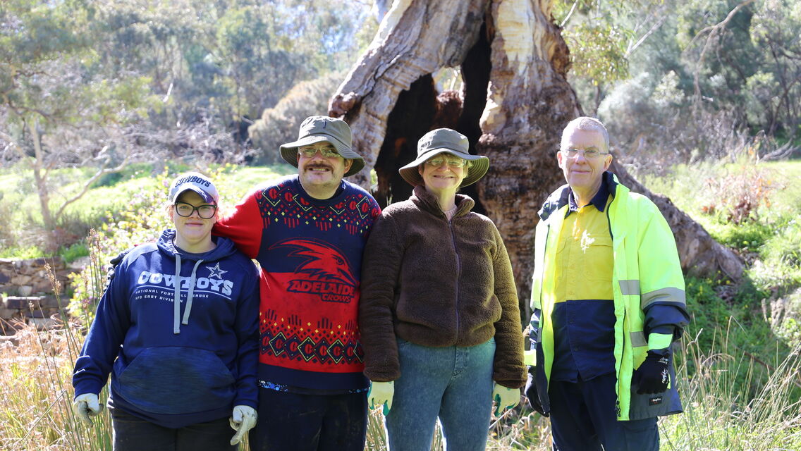 Four individuals standing next to each other outdoors and smiling at camera