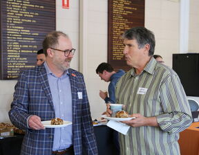 Two men having a conversation with a plate of food in hand