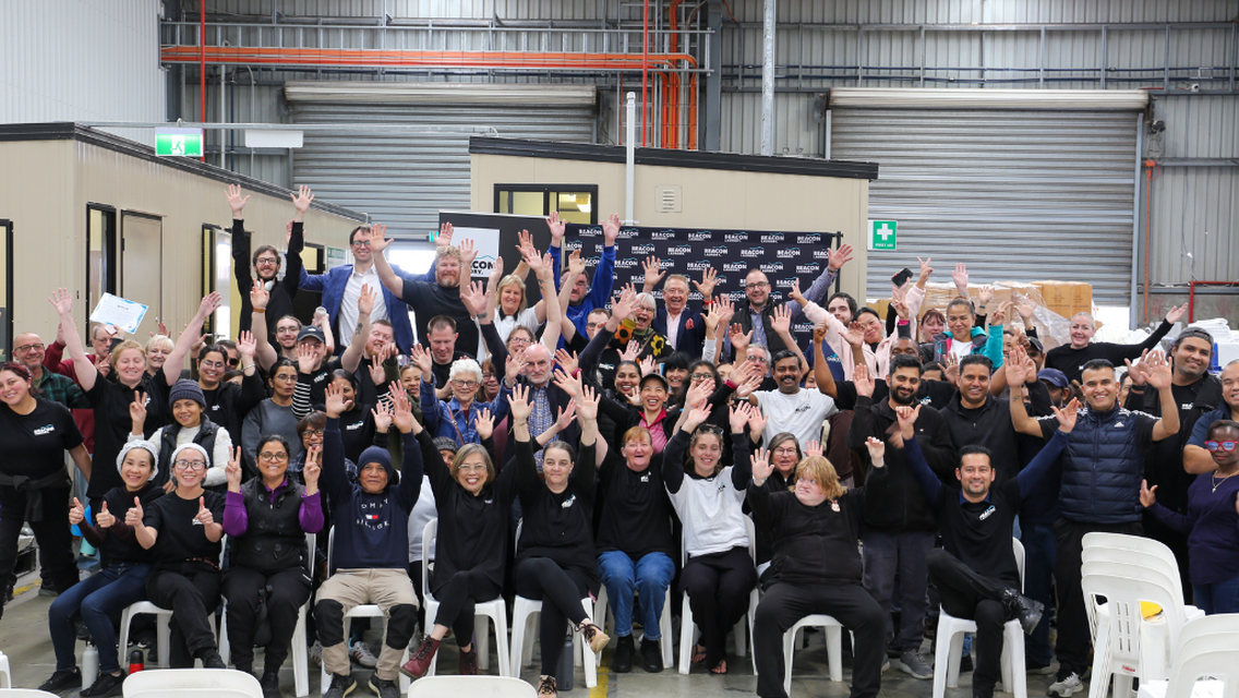 Group of individuals raising hands and smiling at the camera