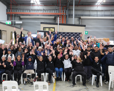 Group of individuals raising hands and smiling at the camera