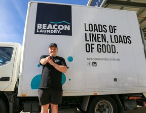 Individual standing next to a white truck with beacon laundry branding