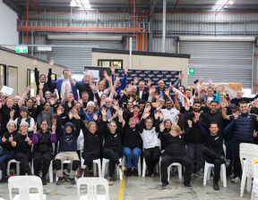 Group of individuals with raised hands smiling and looking at the camera
