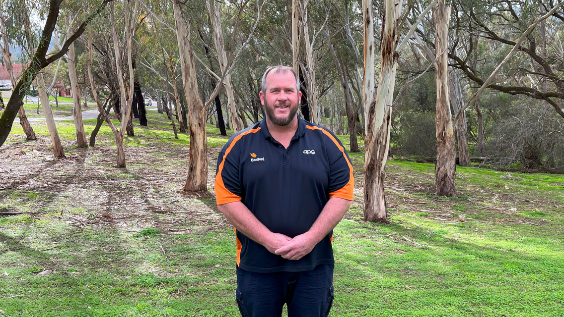 Man wearing navy blue t-shirt surrounded by trees and greenery