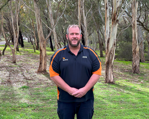 Man wearing navy blue t-shirt surrounded by trees and greenery
