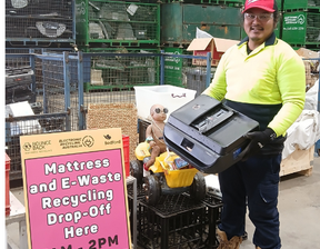 Man with red colour cap and hi-vis jumper holding old printer