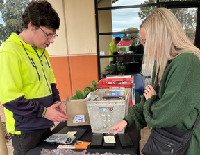 Women looking at purchasing refurbished electronics and man wearing hi-vis jumper standing behind the counter
