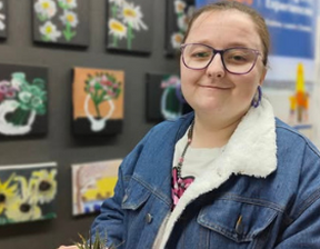 Women wearing denim jacket and specs holding a succulent plant and smiling