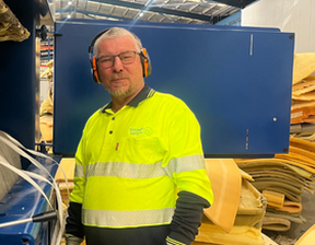 Man wearing hi-vis clothing with ear muffs and gloves looking at camera