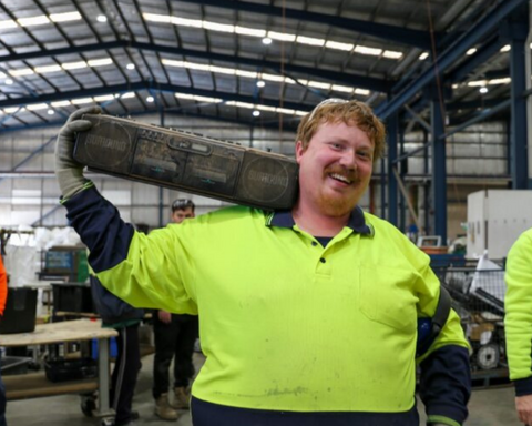 Man wearing hi-vis yellow polo with black colour speaker in hand