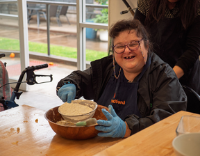 Women sieving flour smiling at camera