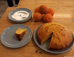 Cake sliced with oranges in the background on plates