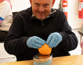 Man wearing blue gloves zesting an orange