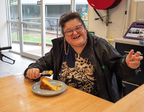 Women enjoying a piece of cake smiling at the camera
